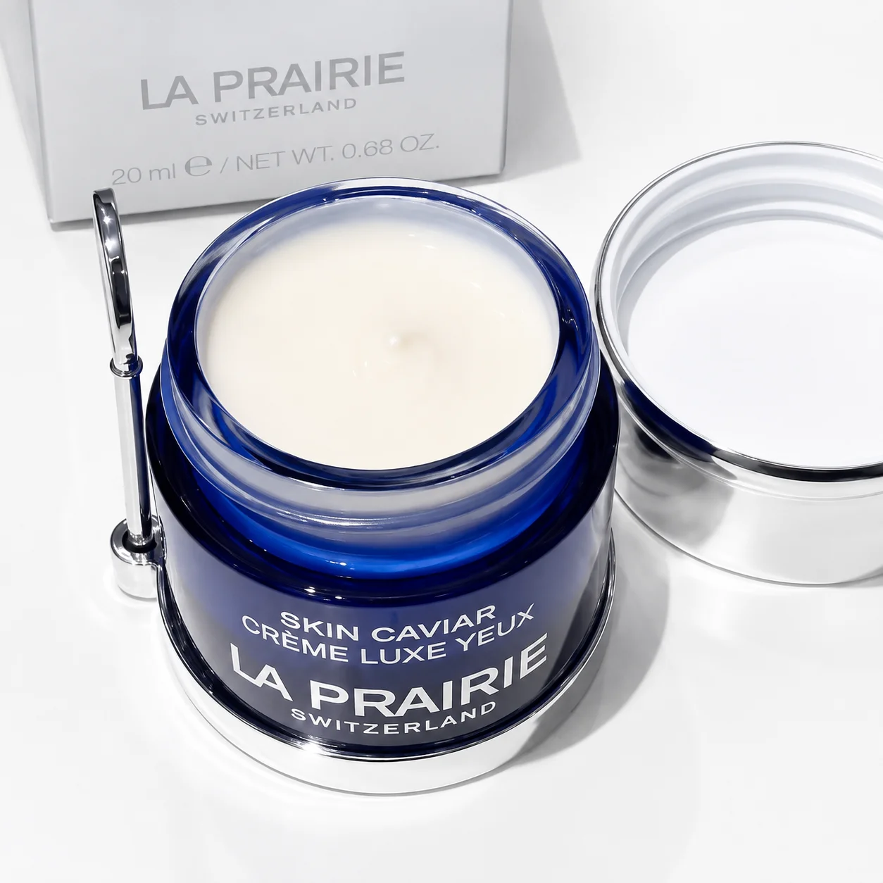 La Prairie Skin Caviar Luxe Eye Cream displayed in a blue jar with an open lid and accompanying box in the background, featuring premium skincare packaging.